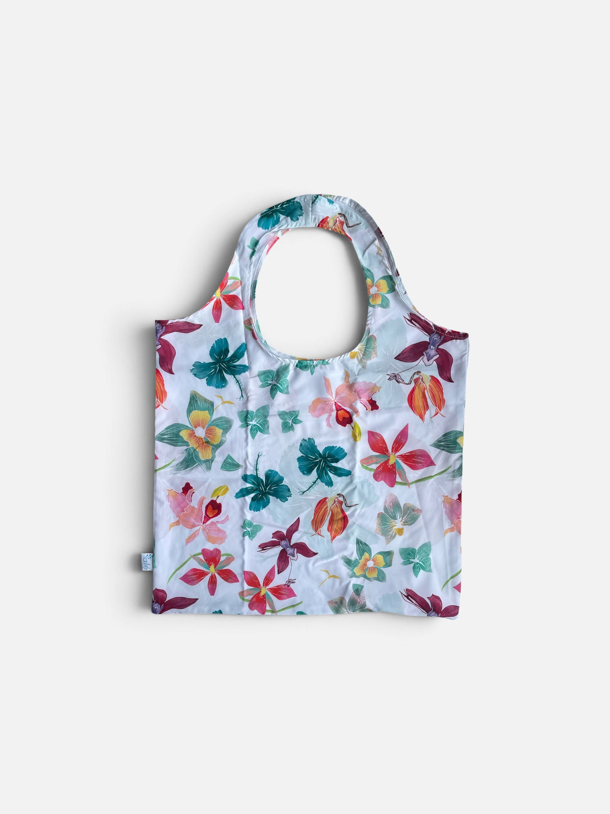 bolsa ecológica flores acuarela Colombia, tote bag plegable estampado floral blanco, bolsa de tela orquídeas para el mercado, bolsa para ir al mercado reutilizable, bolsa plegable para el bolso diario, accesorio sostenible uso diario mujer, regalo ecológico para ella, detalle sostenible mujer amante de las flores, regalo consciente botánico Colombia, foldable eco bag orchid print, reusable market bag Colombia, sustainable tote recycled bottles floral, bolsa plegable Ailé orquídeas. Ailé