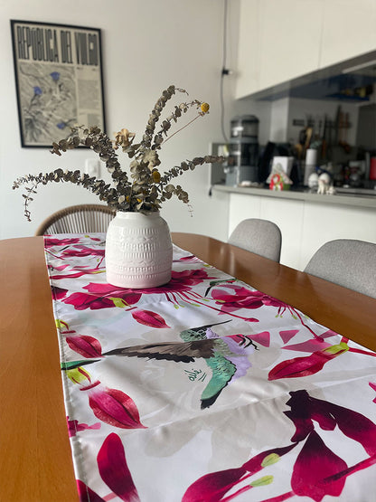 Decoración en mesa de comedor ilustrado con colibríes colombianos entre flores tropicales fucsia, egalo cultura colombiano, Colombian table runner illustrated, colombianos en el exterior y turistas, eco table runner Colombia, decoración colombiana para comedor, Colombian design table runner gift, recycled fabric table runner Colombia, hecho en Colombia, camino de mesa con diseño de fauna colombiana. Ailé