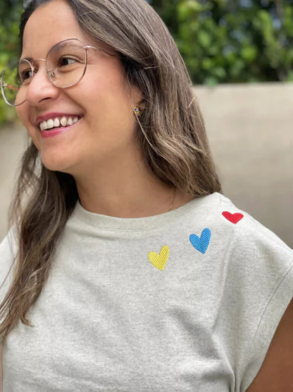 Detalle de corazones bordados a mano en camiseta Ailé, diseño Matu Corazón, regalo colombiano para mujer, camiseta souvenir Colombia, regalo original hecho en Colombia, ropa colombiana para regalar, camiseta artesanal regalo, camiseta corazón bordado colombiana, moda colombiana con corazones, camiseta Matu Ailé, diseño textil corazones Colombia. Ailé