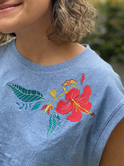 Detalle de flor tropical bordada en camiseta Ailé, diseño Matu Flor, camiseta flor roja bordada, camiseta bordado a mano flor, camiseta azul detalle floral, camiseta hibisco bordado, camiseta flor tropical colores, Colombian tropical flower t-shirt, embroidered flower shirt handmade, Colombia, tropical floral apparel Colombia gift.  Ailé