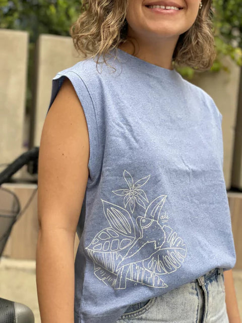 Detalle de tucán ilustrado en camiseta Ailé, diseño Matu Tucán, camiseta ilustración tono sobre tono, camiseta bordado/estampado tucán azul, camiseta línea blanca ilustrada, camiseta hojas tropicales tucán, camiseta arte lineal aves, Colombian toucan t-shirt, toucan print shirt handmade, Colombia tropical bird clothing gift, illustrated toucan apparel Colombia. Ailé