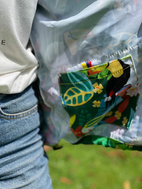 Chaqueta con bolsillo colombiano hojas de selva en verde y azul. "Colombia" tropical Colombia souvenir, eco friendly Colombia jacket design, chaquetas rompevientos institucionales ecológicas, chaqueta rompevientos para regalo de cumpleaños, rompevientos para festival de música, chaquetas con diseños de aves colombianas, chaquetas antifluido de moda colombia, rompevientos liviano de tela reciclada. Ailé