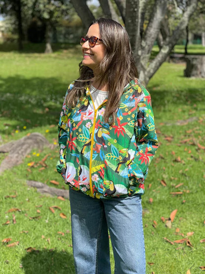 Chaqueta biodiversidad colombiana, ilustrado con tucanes y flora tropical colombiana, heliconias y hojas de selva diseño original Ailé Colombia, estampado tropical colombiano, diseño selva Colombia, chaqueta tela reciclada Colombia, chaqueta botellas recicladas Colombia, chaqueta impermeable reciclada Colombia, chaqueta con capota colombiana, chaqueta rompevientos ecológica Colombia. Ailé