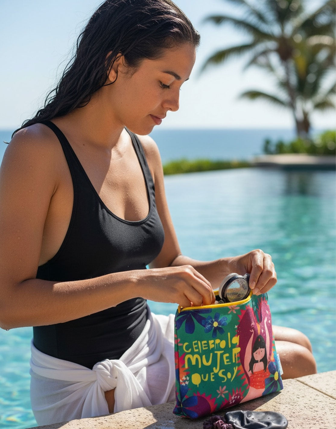Cosmetiquera impermeable "Celebro la mujer que soy" junto a piscina tropical — neceser de viaje colombiano, cosmetiquera de playa, regalo mujer extranjera. Ailé