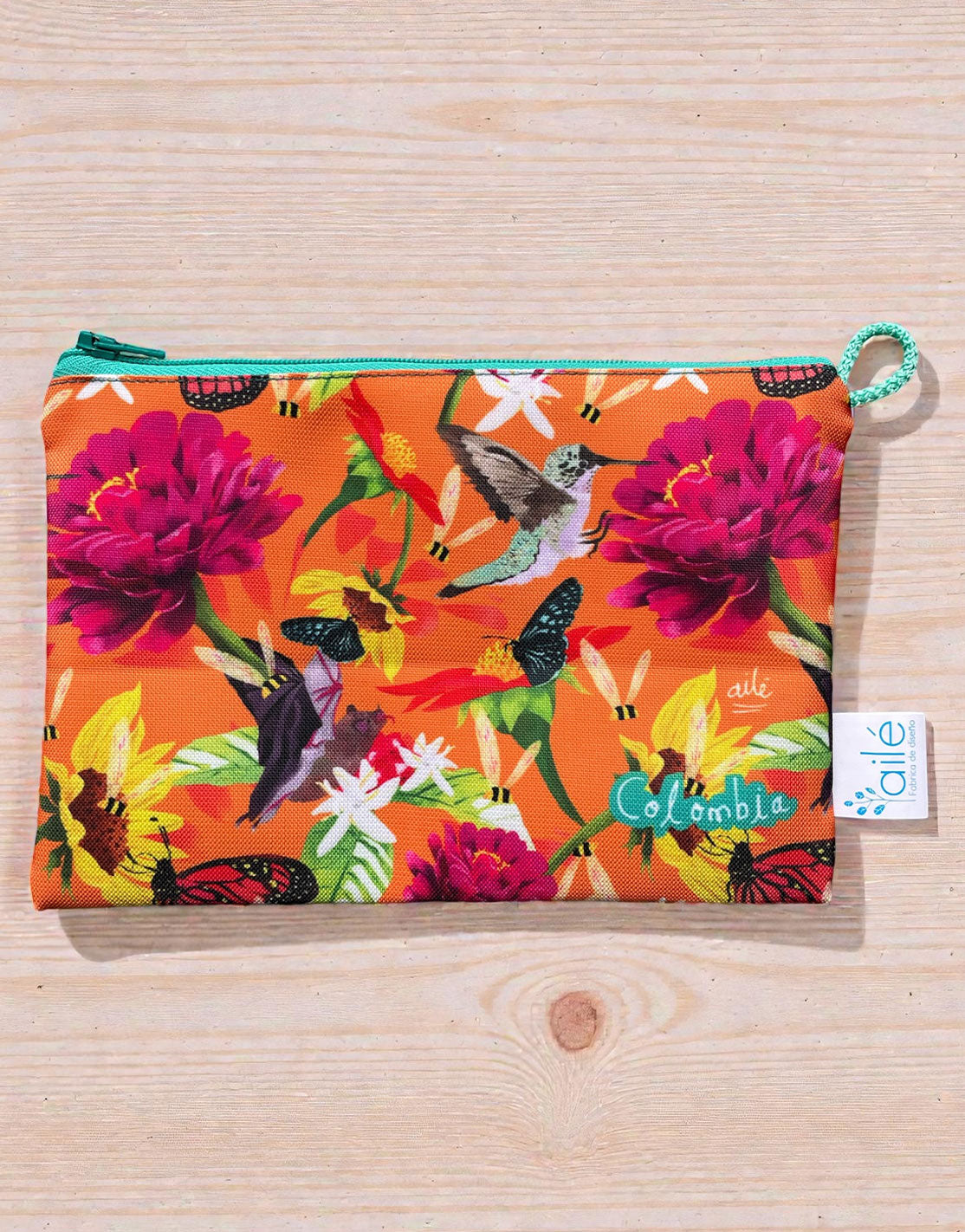 Cosmetiquera ilustrada con polinizadores colombianos — colibríes, mariposas y abejas entre flores tropicales, cosmetiquera pequeña colombiana, regalo cosmetiquera colombiana, cosmetiquera grande colombiana, souvenir cosmetiquera Colombia, regalo ecológico neceser Colombia, neceser pequeño ecológico Colombia, neceser grande tela reciclada Colombia, cosmetiquera tamaño viaje Colombia, recycled fabric cosmetic bag Colombia. Ailé