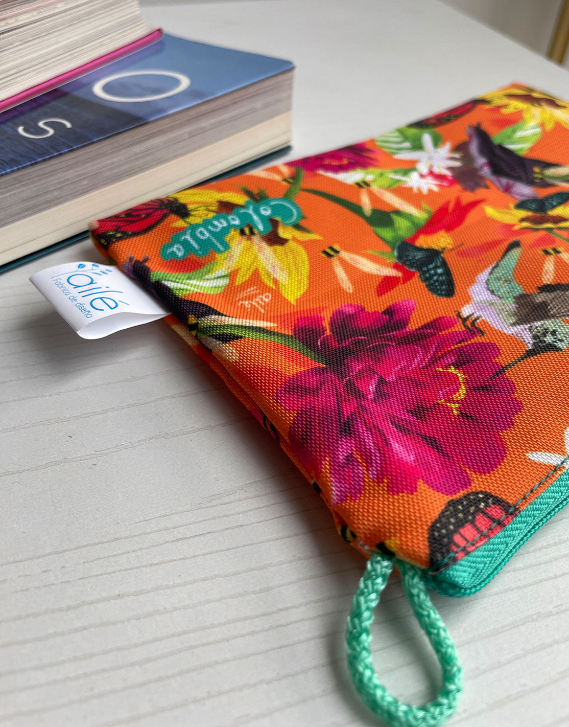 Neceser con diseño de colibríes, mariposas colombianas y flores tropicales naranja, cosmetiquera sostenible con fauna colombiana ilustrada,  neceser tela reciclada impermeable con diseño colombiano, Colombian illustrated cosmetic bag, cosmetiquera regalo original Colombia, cosmetiquera con diseño colombiano original, neceser con ilustración colombiana, Colombia souvenir makeup bag. Ailé