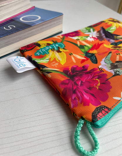 Neceser con diseño de colibríes, mariposas colombianas y flores tropicales naranja, cosmetiquera sostenible con fauna colombiana ilustrada,  neceser tela reciclada impermeable con diseño colombiano, Colombian illustrated cosmetic bag, cosmetiquera regalo original Colombia, cosmetiquera con diseño colombiano original, neceser con ilustración colombiana, Colombia souvenir makeup bag. Ailé