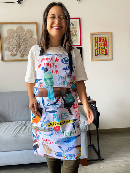 Mujer usando delantal ilustrado con aves colombianas — Carriqui, Tangara y Azulejo — regalo colombiano de cocina, delantal ilustrado, regalos sostenible, souvenir colombiano. Ailé