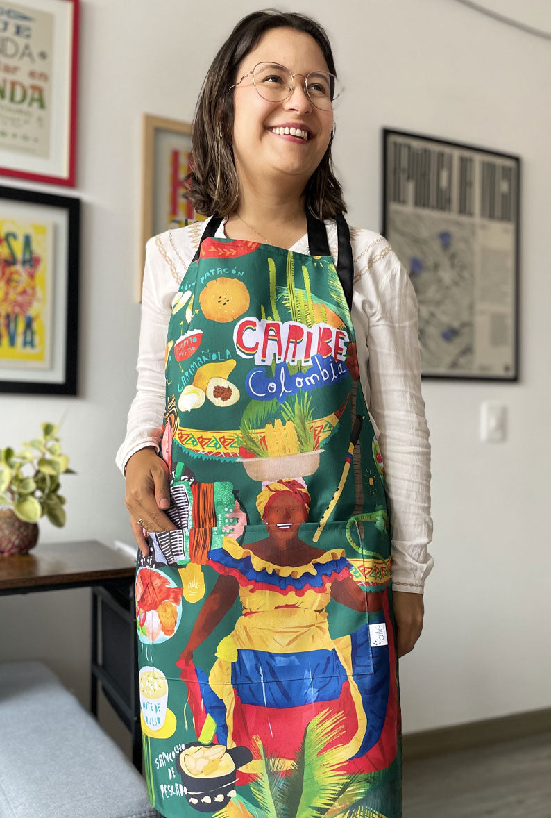 Delantal ilustrado "Caribe Colombia" con palenquera, acordeonero y gastronomía costeña — regalo colombiano cocina, souvenir del Caribe colombiano, gastronomía costeña, regalo de Cartagena, regalo de Barranquilla, regalo de santa marta, recuerdo de viaje original, regalos de la costa. Ailé