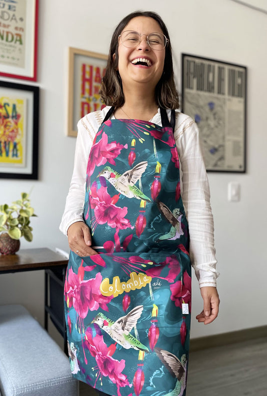 Delantal ilustrado con colibríes colombianos entre flores tropicales fucsia — regalo colombiano de cocina, delantal ilustrado, colombianos en el exterior y turistas, regalo cultura colombiana. Diseño Ailé