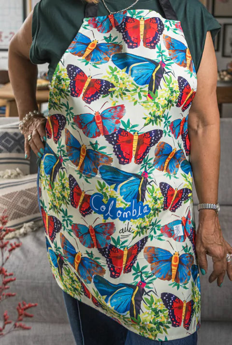 Delantal impermeable de cocina ilustrado con mariposas colombianas en azul y rojo, souvenir de biodiversidad, diseño original Ailé Colombia, estampado mariposas Colombia, diseño mariposas tropicales, regalo cultural colombia, pechera, regalo colombiano de cocina. Ailé
