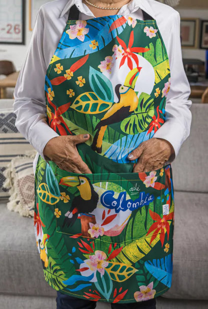 Delantal de cocina ilustrado con tucanes y flora tropical colombiana, heliconias y hojas de selva diseño original Ailé Colombia, estampado tropical colombiano, diseño selva Colombia, delantal ilustrado, regalo colombiano de cocina, colombianos en el exterior y turistas, regalo cultural colombia. Ailé