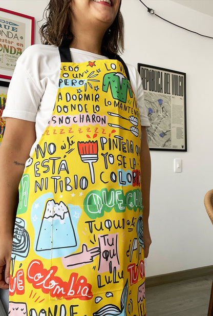 Delantal impermeable con diseño de frases Colombianas - acompañadas de íconos colombianos: sombrero vueltiao, aguapanela, colino, sirena, casas de pueblo. Regalo de cocina colombiano, delantal ilustrado, souvenir colombiano. Ailé