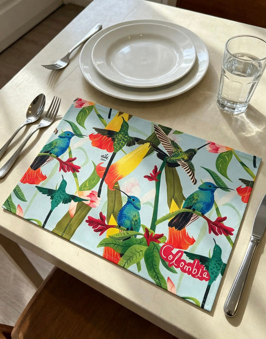 Individual Colibrí Colombia Ailé, ilustración de aves y flores tropicales en tela, Individual Colibrí Ailé sobre mesa servida, colibríes y flores tropicales colombianas, Individual Ailé Colibrí, decoración de mesa inspirada en la biodiversidad colombiana, individual fondo celeste colibríes, individual flores tropicales rojas amarillas, diseño botánico y fauna mesa, colibrí Colombia decoración mesa,Colombia mayor diversidad colibríes mundo, fauna colombiana individual textil, Colombian hummingbird placemat
