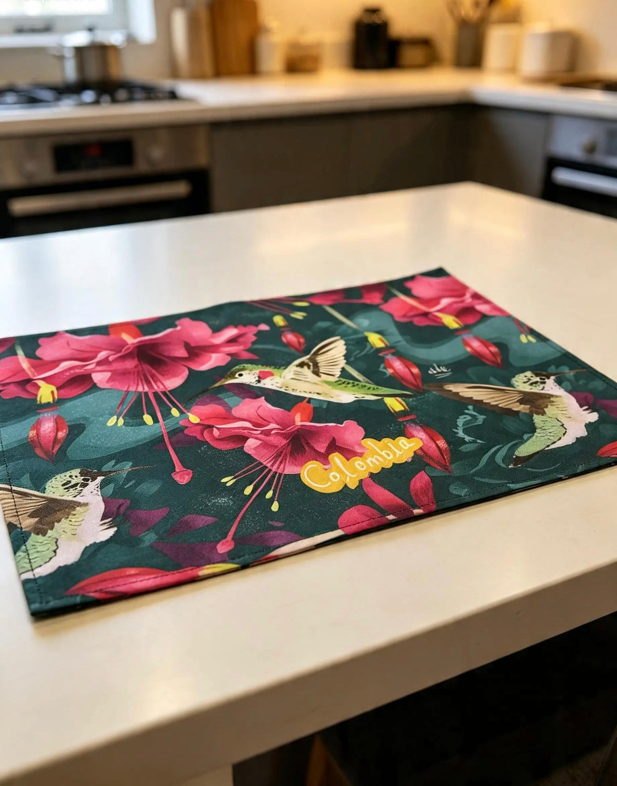 Individual de tela impermeable, ilustrado con colibríes colombianos entre flores tropicales fucsia, regalo colombiano para el hogar, individual ecológico colombiano, detalle colombiano para la mesa, individuales de mesa colombianos, individual tela reciclada Colombia, individuales ilustrados Colombia, individual sostenible con diseño colombiano, individual hecho con botellas recicladas Colombia,  colombian illustrated home accessories, individuales decorativos Colombia, regalo para colombianos, ailé.