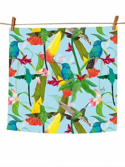 Pañoleta pequeña con ilustración "Colibrí Azul Colombia" — fondo celeste con colibríes en verde esmeralda, azul y amarillo, entre flores tropicales rojas y rosas, regalo Día de la Madre pañoleta Colombia, pañoleta grande ilustrada Colombia , pañoleta regalo mujer Colombia, pañoleta regalo Amor y Amistad Colombia, pañoleta cabello Colombia, pañoletas cuadradas grandes para hacer top souvenir Colombia pañoleta turista, regalo original mujer pañoleta Colombia. Ailé
