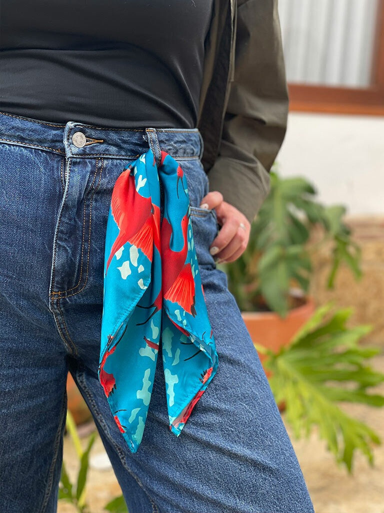 Formas de usar pañoleta como accesorio femenino, con ilustración de corocora roja, ibis escarlata o garza roja de Colombia, pañoleta cabeza Colombia, pañoleta mediana ilustrada Colombia, regalo pañoleta colombiana original, pañoleta multiusos ilustrada, regalo accesorio colombiano ilustrado, accesorio con identidad colombiana, pañoleta playera colombiana, pañoleta amarrada como blusa mujer, complementos de moda para viajeras colombia, Colombia souvenir bandana illustrated. Ailé
