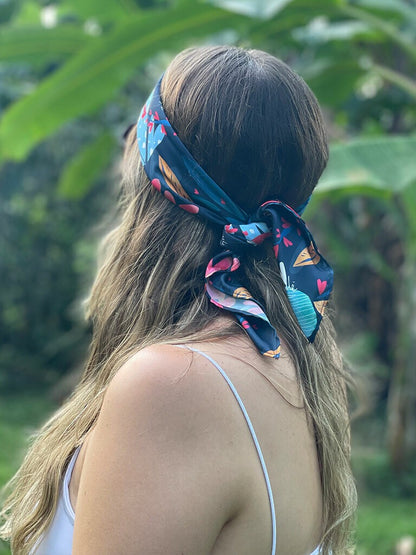 Modelo usando una pañoleta ecológica como bandana para el cabello con estampado de flores en forma de corazón, pañoleta amarrada como blusa mujer, complementos de moda para viajeras colombia, Colombia souvenir bandana illustrated, pañoleta decorativa Colombia, bandanas de tela reciclada de plástico, pañoleta accesorio moda Colombia, pañoleta bolsillo Colombia, pañoleta pequeña ilustrada Colombia, souvenir y regalo accesorio Colombia, accesorio moda ecológico Colombia. Ailé