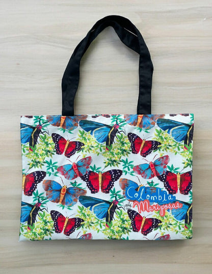Tote bag impermeable, ilustrado mariposas de Colombia entre ramas tropicales y biodiversidad — regalo colombiano fauna silvestre, souvenir mariposas Colombia, regalo sostenible, recuerdo de viaje original, souvenir mariposas Colombia, regalo mariposas tropicales, bolso playa Colombia diseño, tote bag impermeable Colombia, regalo corporativo tote bag colombiana, bolso diario con diseño colombiano, tote bag trabajo Colombia ilustrada, tote bag ecológica Colombia.Aile